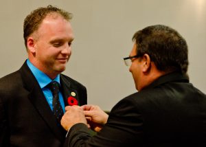 Councillor Aaron Buckingham has his City of Lloydminster pin placed on his suit by Lloydminster mayor Gerald Aalbers. Photo by James Wood/106.1 The Goat/Vista Radio