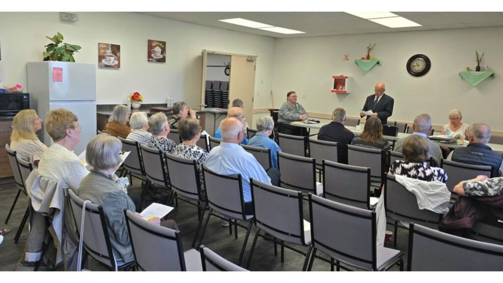 MLA Colleen Young seated far left listens to president Graham Brown delivering his report at the Lloydminster Concerned Citizens for Seniors Care AGM. | Photo: Gerry Lampow 106.1 The Goat/Vista Radio.