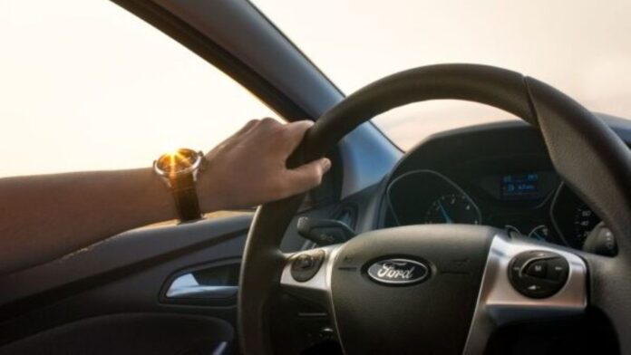 Driver's hand on steering wheel.